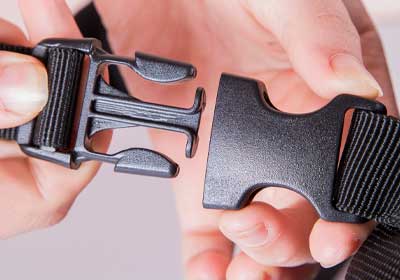 Close-up of a black plastic side release buckle clipped onto outdoor gear strap