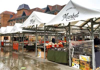 Market stall covered with durable tarpaulin protecting goods from rain in the UK